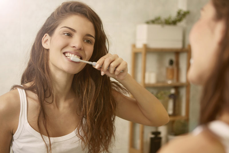 An image of a woman brushing her teeth.