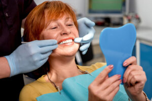 An image of a woman sitting in a dental chair getting erosion and tissue repair.