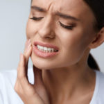 a dental patient in need of a tooth extraction and dental implant experiencing pain.