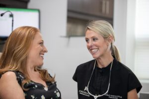 Dr. Anderson smiling with a patient in her practice after improving her smile with exosome therapy.