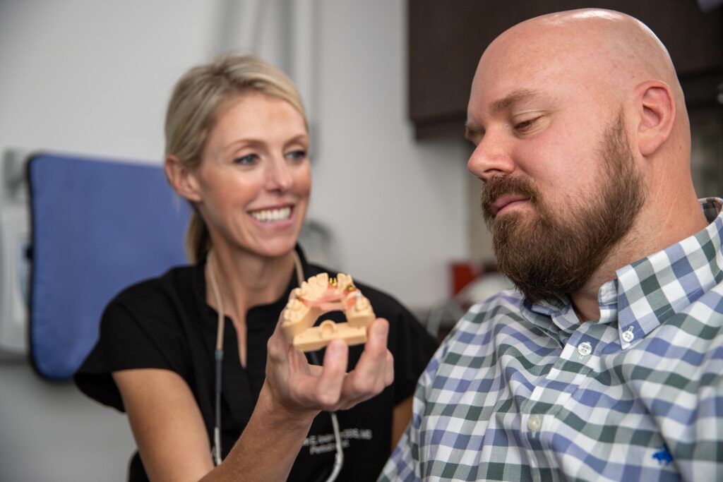 Dr. Anderson showing a patient a full mouth dental implant model for his full mouth dental implant procedure.